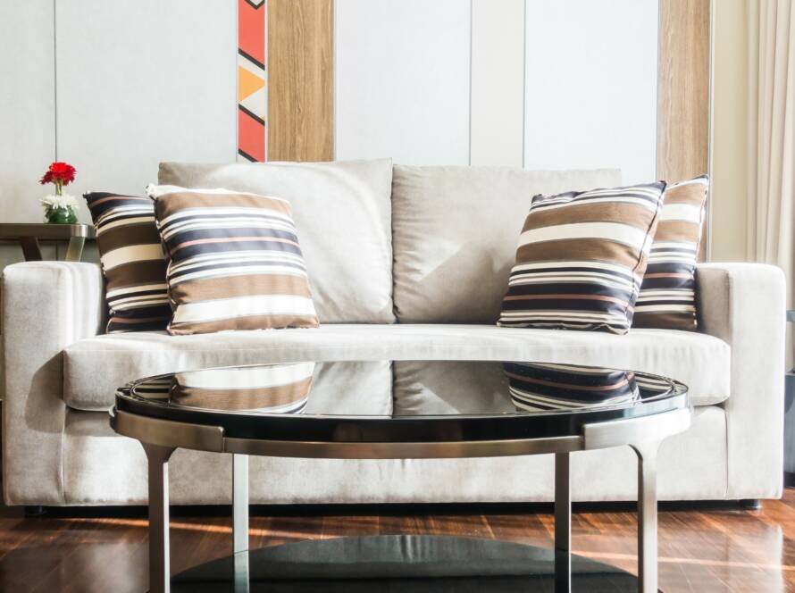 Luxury cream upholstered sofa with designer cushions and glass coffee table in a modern living room