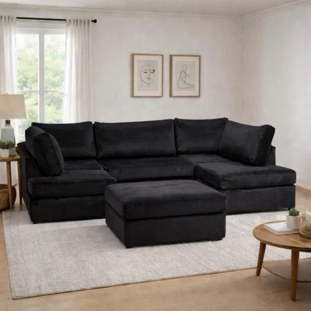 Black U shape plush settee with matching ottoman in a modern living room.